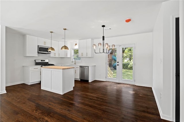 kitchen with light countertops, hanging light fixtures, appliances with stainless steel finishes, white cabinets, and a kitchen island