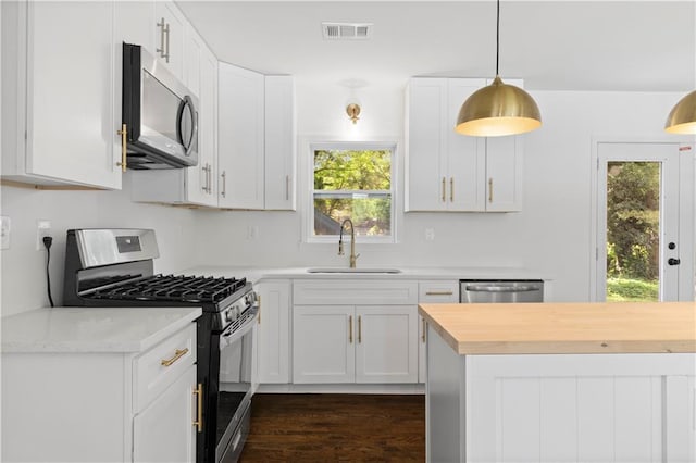 kitchen with visible vents, appliances with stainless steel finishes, white cabinetry, pendant lighting, and a sink