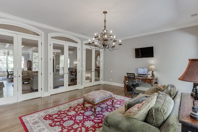 living room featuring a chandelier, ornamental molding, french doors, and wood finished floors