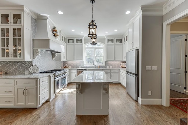 kitchen featuring decorative light fixtures, light wood-type flooring, light stone countertops, and stainless steel appliances