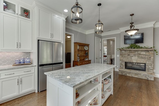kitchen featuring freestanding refrigerator, white cabinetry, wood finished floors, light stone counters, and open shelves