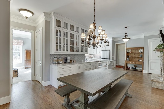 dining area featuring baseboards, crown molding, wood finished floors, and an inviting chandelier