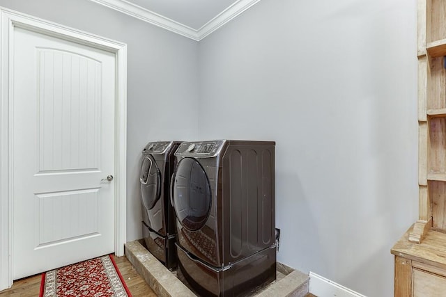 clothes washing area with wood finished floors, crown molding, washer and dryer, and laundry area