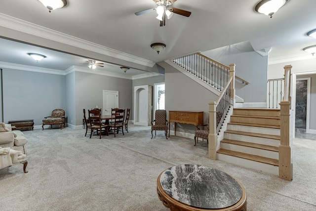 living area featuring carpet flooring, a ceiling fan, and stairs