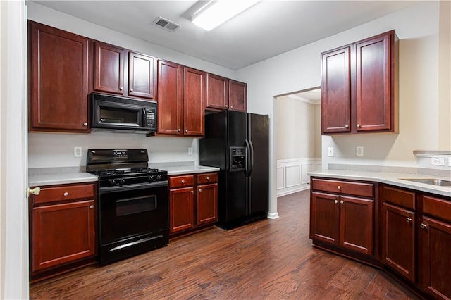 kitchen with black appliances and dark hardwood / wood-style flooring