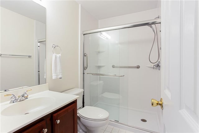 bathroom featuring vanity, a shower with door, tile patterned flooring, and toilet