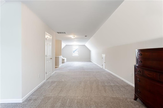 bonus room with light colored carpet and vaulted ceiling