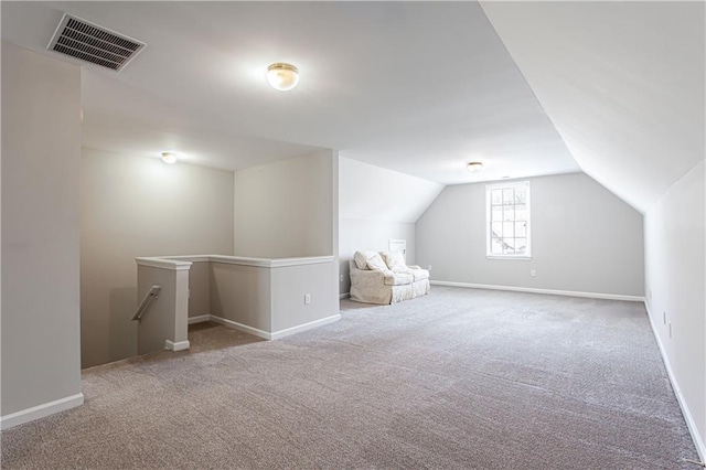 additional living space featuring light colored carpet and vaulted ceiling