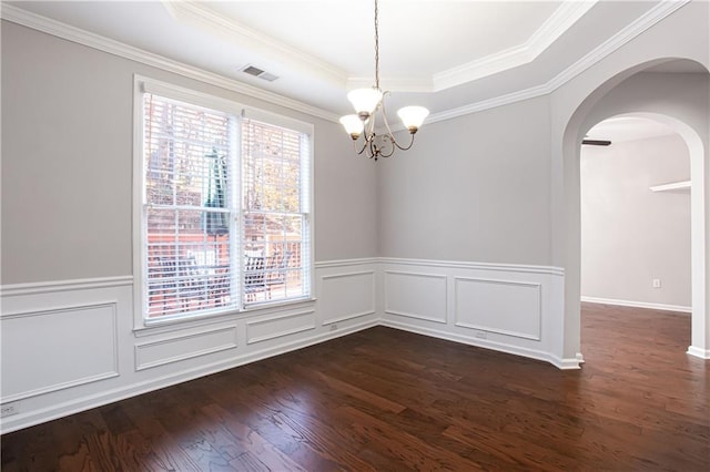 spare room with a raised ceiling, dark hardwood / wood-style floors, an inviting chandelier, and crown molding