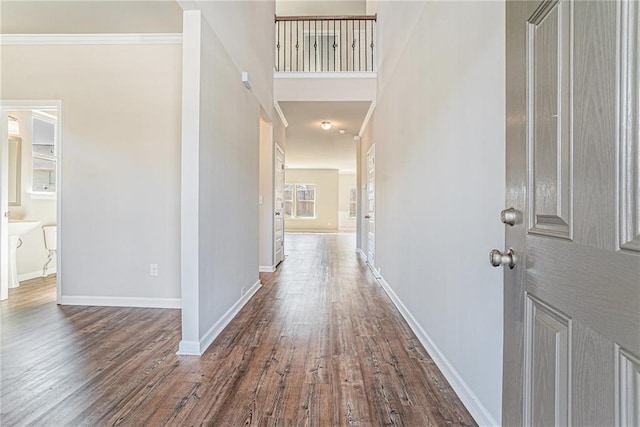 corridor featuring crown molding, baseboards, and dark wood-type flooring