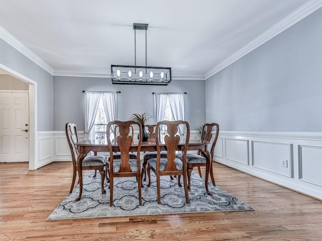 5090 Eubanks Rd, Woodstock, GA 30188 - dining room featuring a chandelier, a decorative wall, ornamental molding, light wood finished floors, and wainscoting