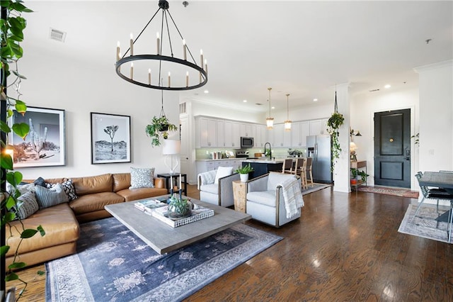 living room with ornamental molding, dark hardwood / wood-style flooring, sink, and a notable chandelier