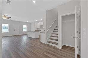 unfurnished living room featuring stairway and dark wood-type flooring