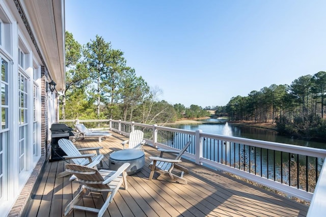 wooden terrace featuring grilling area and a water view