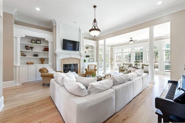 living room featuring ceiling fan, a fireplace, crown molding, and light wood-type flooring