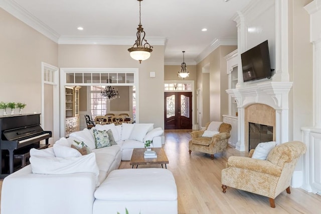 living area featuring crown molding, recessed lighting, light wood-type flooring, and a high end fireplace