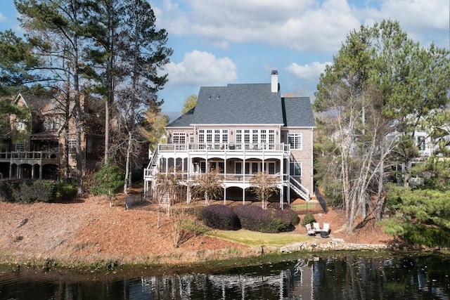 back of house featuring a deck with water view, a chimney, and stairs