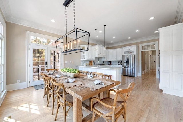 dining space with french doors, baseboards, light wood-style floors, and ornamental molding