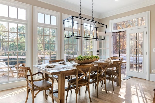 dining area with crown molding, a notable chandelier, and light wood-type flooring