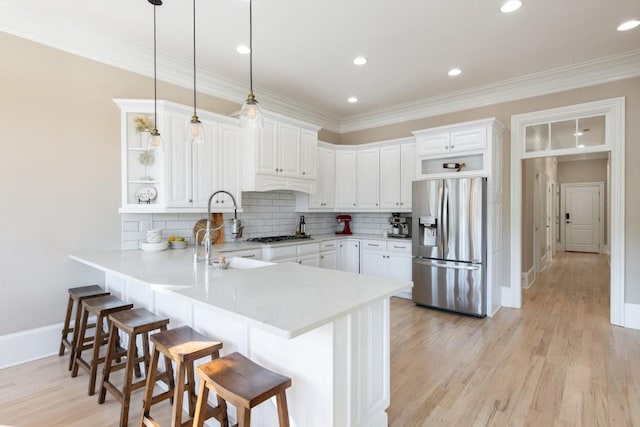 kitchen featuring kitchen peninsula, white cabinetry, stainless steel appliances, and decorative light fixtures