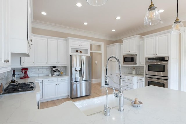 kitchen featuring white cabinets, decorative backsplash, stainless steel appliances, and hanging light fixtures