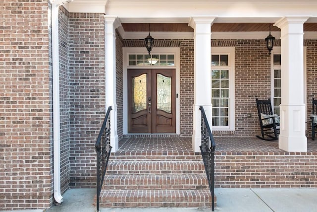 property entrance featuring brick siding, french doors, and a porch