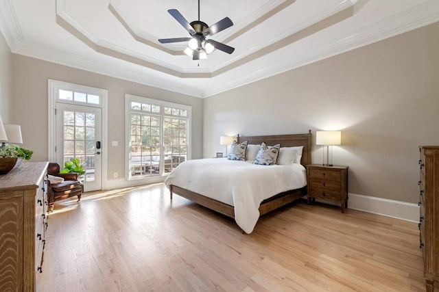 bedroom featuring access to exterior, ceiling fan, crown molding, a tray ceiling, and light wood-type flooring