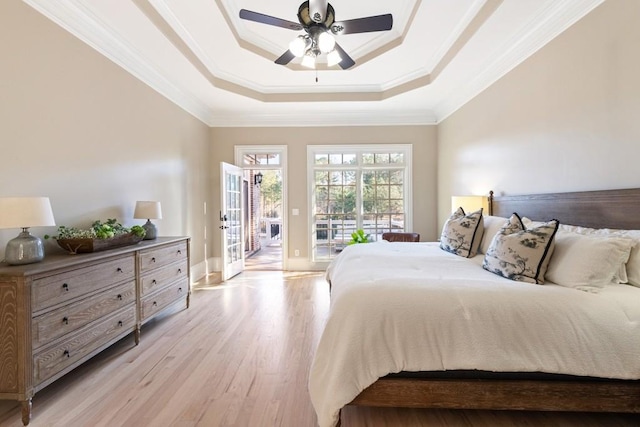 bedroom with ceiling fan, access to exterior, ornamental molding, a tray ceiling, and light hardwood / wood-style floors