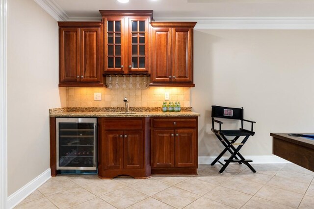 bar with decorative backsplash, light stone countertops, crown molding, and wine cooler