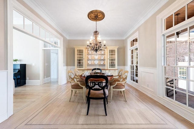 dining area featuring light hardwood / wood-style floors, crown molding, and a notable chandelier