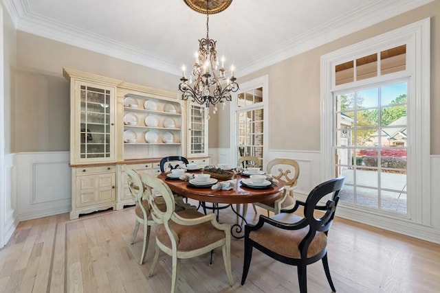 dining space with crown molding, light wood-type flooring, and a notable chandelier