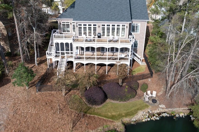 rear view of house featuring stairway, a deck, and a shingled roof