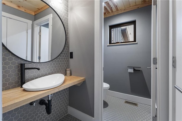 bathroom with sink, tile patterned floors, decorative backsplash, wooden ceiling, and toilet