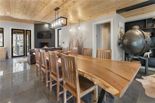 dining room featuring wood ceiling, a large fireplace, and a chandelier