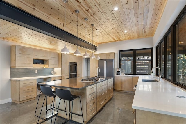 kitchen featuring a large island with sink, sink, light brown cabinetry, and decorative light fixtures