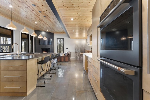 kitchen featuring a kitchen bar, wood ceiling, light brown cabinets, double oven, and pendant lighting