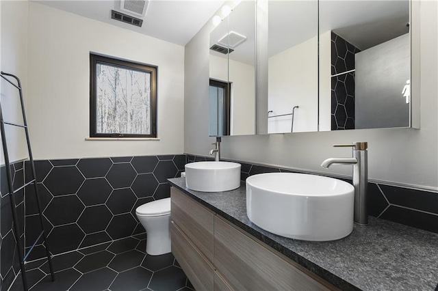 bathroom with vanity, tile walls, tile patterned floors, and toilet