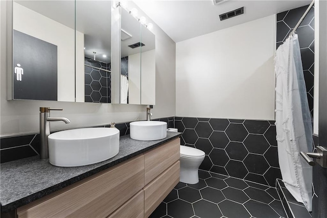 bathroom featuring tile walls, tile patterned flooring, a shower with shower curtain, vanity, and toilet