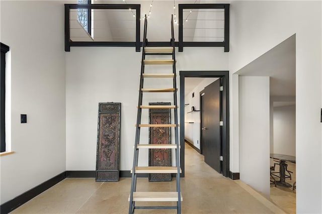 stairs with a towering ceiling and concrete floors