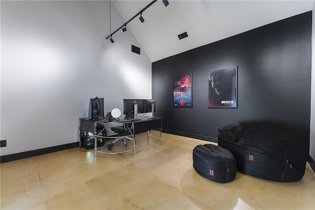 home office featuring track lighting, concrete floors, and high vaulted ceiling