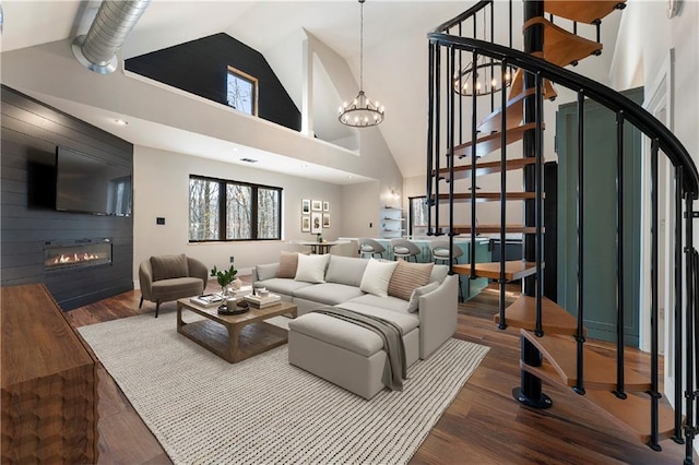 living room featuring hardwood / wood-style flooring, high vaulted ceiling, a large fireplace, and an inviting chandelier