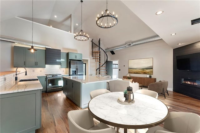 kitchen with sink, hanging light fixtures, stainless steel appliances, light stone countertops, and a kitchen island