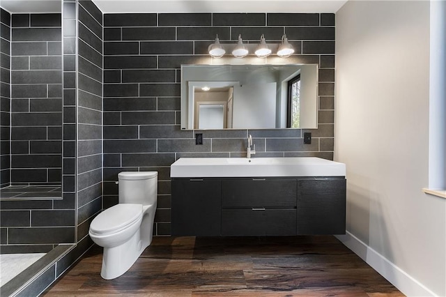 bathroom with tile walls, decorative backsplash, hardwood / wood-style flooring, vanity, and toilet