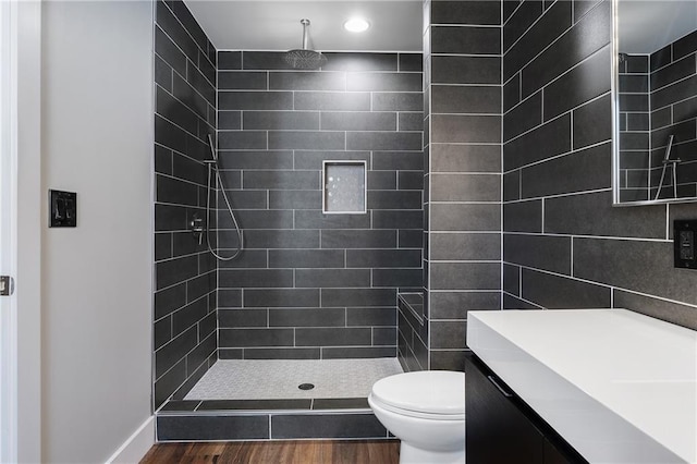 bathroom with hardwood / wood-style flooring, toilet, and tiled shower