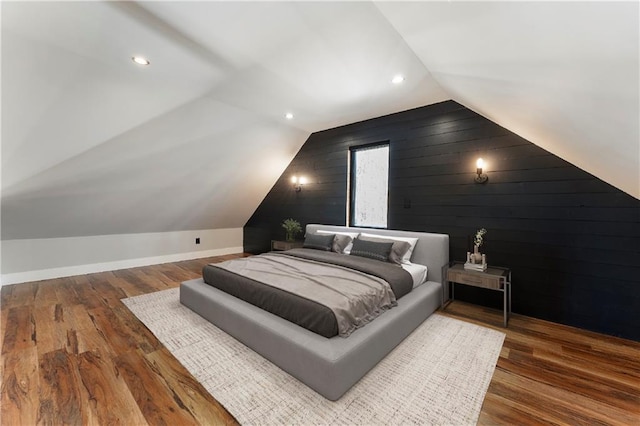 bedroom featuring vaulted ceiling, hardwood / wood-style floors, and wood walls