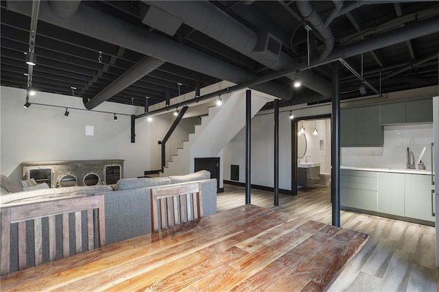 basement featuring rail lighting, sink, and light wood-type flooring