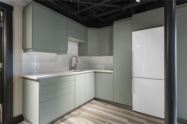 kitchen featuring tasteful backsplash, sink, light wood-type flooring, and white refrigerator