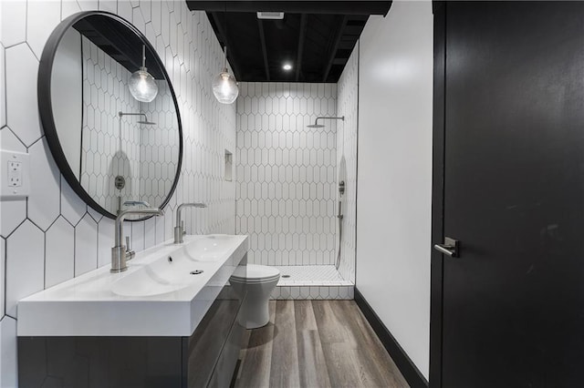 bathroom with vanity, toilet, hardwood / wood-style floors, and a tile shower