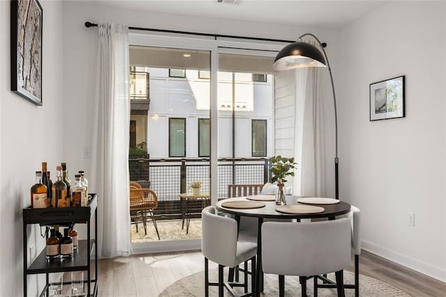 dining room featuring wood finished floors, a healthy amount of sunlight, baseboards, and visible vents