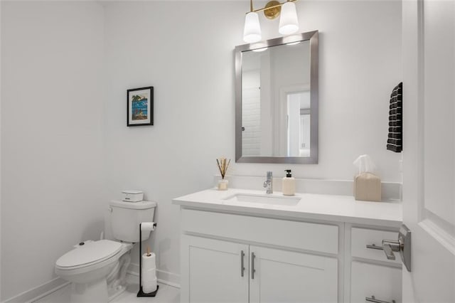 bathroom featuring toilet, vanity, and baseboards